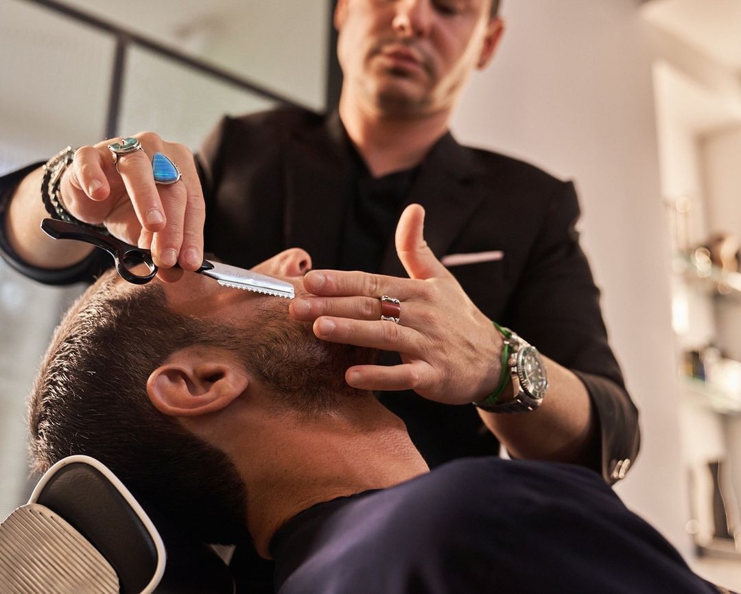 Male stylist shaving man beard at Brazilian Court Salon